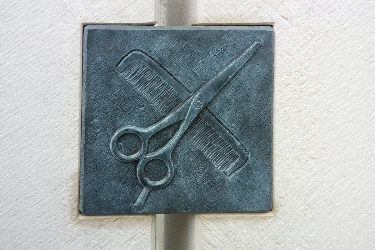 Grabstein für Friseure mit dunkler Platte mit eingravierter Schere und Kamm